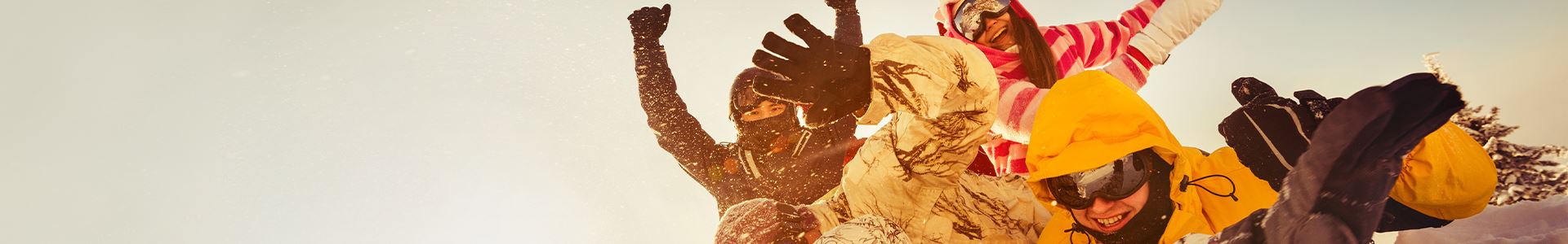 Photography displaying a group of four friends "heaped," waving with their hands to those who see the image and displaying smiling faces. They are all well equipped with snow gear, which includes: eye mask and warm and waterproof clothing and gloves.